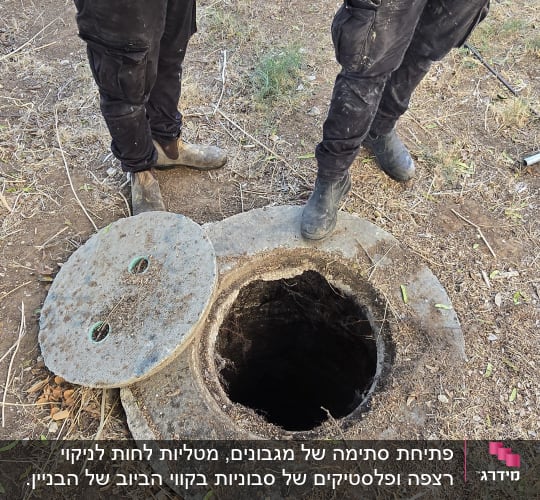 עובדים ליד פתח ביוב עם מכסה פתוח